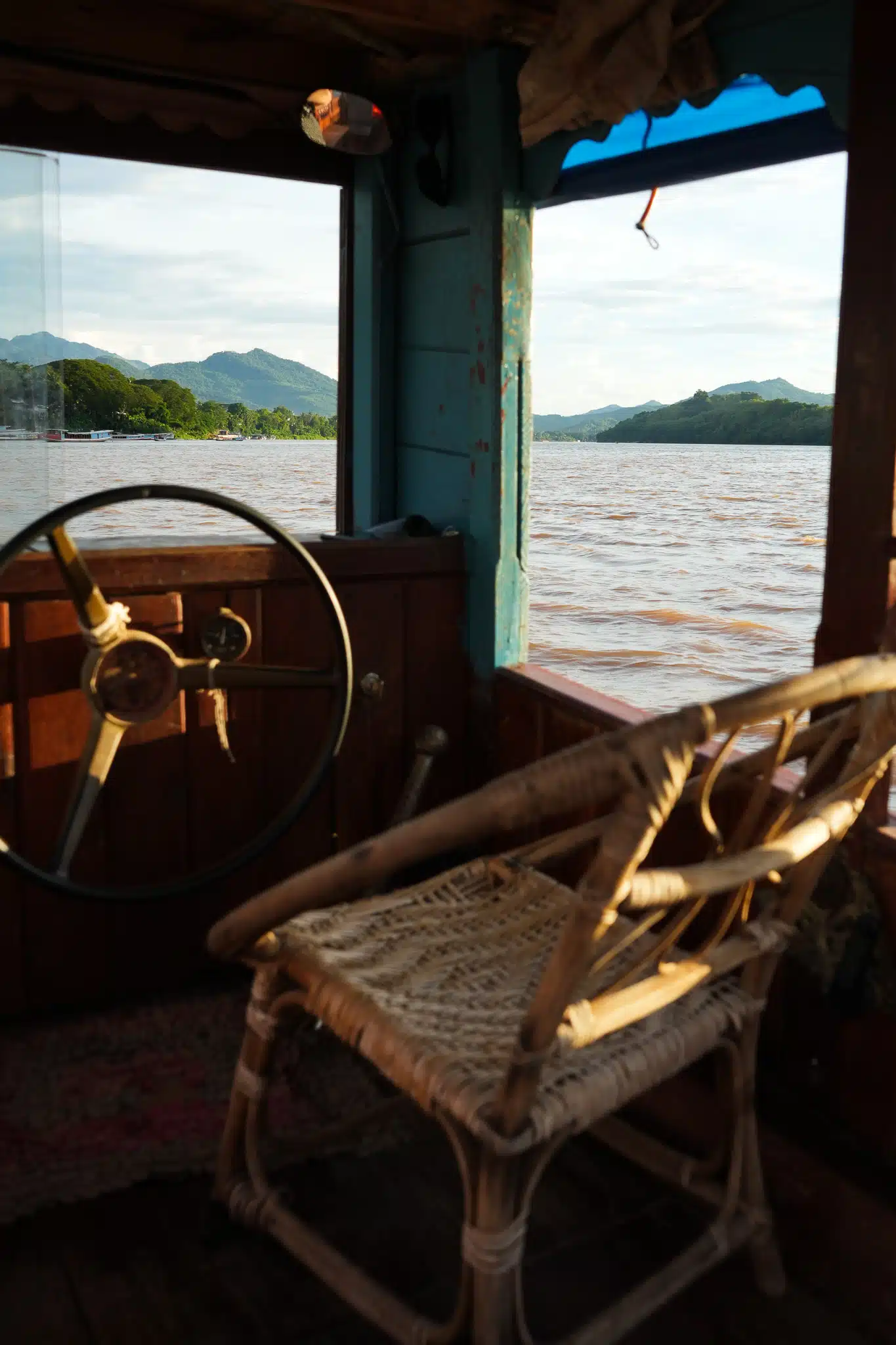 Chair at the front of the wheel of a boat in the middle of Mekong River in Luang Prabang