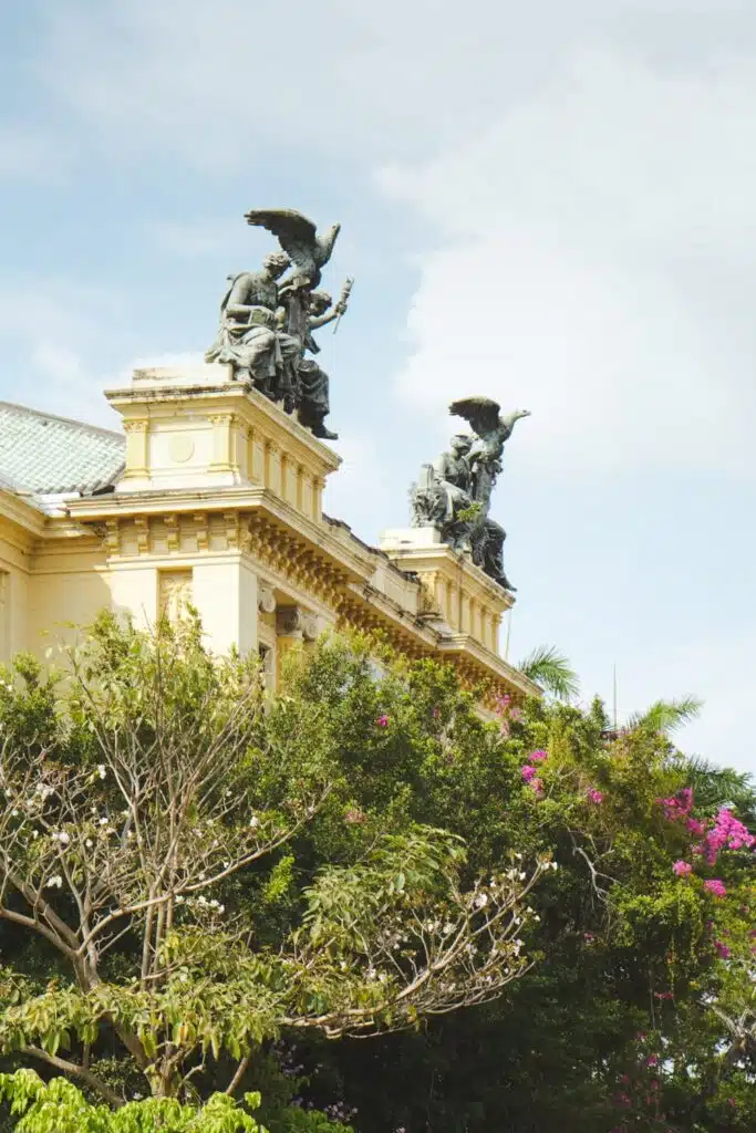 View of an old yellow building in Santa Ana topped with huge statues of women and eagles
