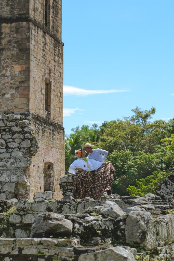 A couple dressed in traditional Panamanian clothes is posing for a photo next to the Panama Viejo Ruins in Panama City