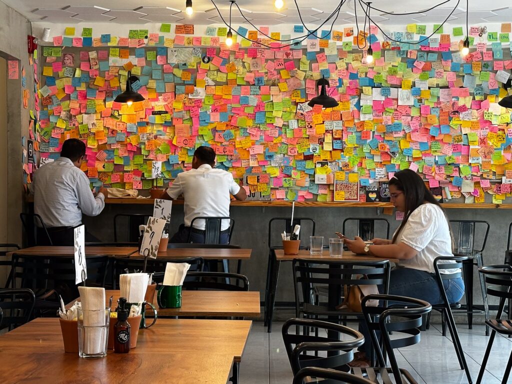 a wall full of post it notes in a cafe