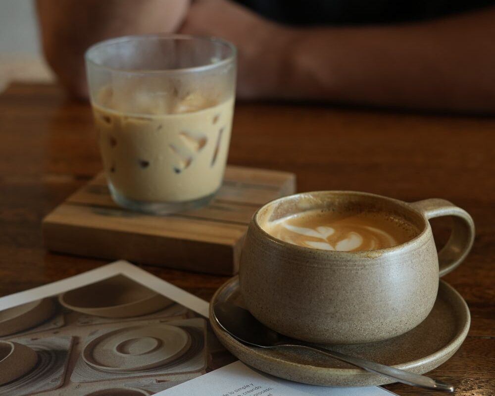 a cup of coffee with latte art and an iced coffee in a cafe